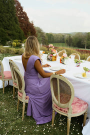 Robe longue pailletée fendue portée par une femme, assise, table dressée, chaise dorée
