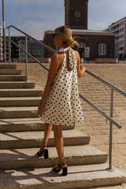 Robe à pois col montant portée par une femme, vue de dos, escalier, nœud dans le dos