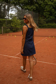 Robe courte en jean portée par une femme, vue de dos, terrain, raquette