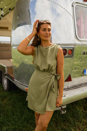 Robe courte taille resserrée portée par une femme, vue de trois-quarts, main dans les cheveux, camping-car