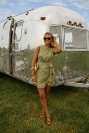 Robe courte taille resserrée portée par une femme, silhouette entière, camping-car, herbe