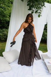Robe longue effet plissé portée par une femme, silhouette entière, coussins, chaussures à la main