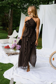 Robe longue effet plissé portée par une femme, silhouette entière, drapés blancs, chaussures à la main