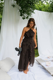 Robe longue effet plissé portée par une femme, silhouette entière, drapés blancs, plan large
