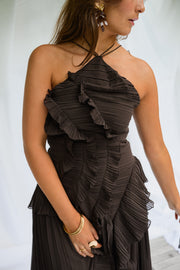 Robe longue effet plissé portée par une femme, vue rapprochée, volants, bijoux