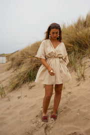 Robe cache-cœur à manches courtes portée par une femme, silhouette entière, dunes, sandales