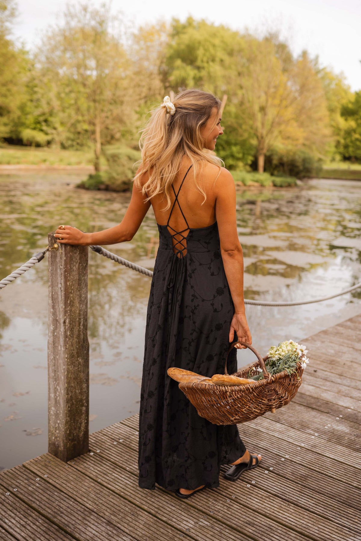 Robe brodée à poches portée par une femme, vue de dos, ponton, panier