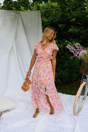 Robe fleurie longue à volants portée par une femme, vue de trois-quarts, fente, vélo