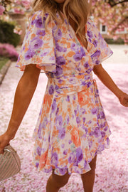 Robe courte fleurie cache-cœur portée par une femme, vue rapprochée, manche papillon, jupe