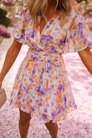 Robe courte fleurie cache-cœur portée par une femme, vue rapprochée, décolleté croisé, ceinture