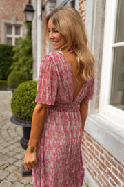 Robe plissée à col V portée par une femme, vue de trois-quarts, fenêtre, cheveux blonds