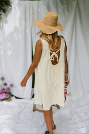 Robe éponge à dos ouvert portée par une femme, vue de profil, drapés blancs, chapeau de paille