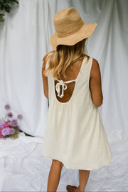 Robe éponge à dos ouvert portée par une femme, vue de dos, chapeau de paille, drapés blancs