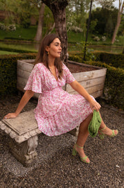 Robe à volants col V portée par une femme, assise, banc en pierre, sac vert