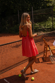 Robe vichy à bretelles portée par une femme, en marchant, balles de tennis, court