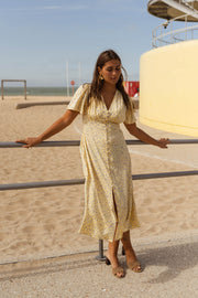 Robe satinée à boutons portée par une femme, vue de face, plage, bras écartés