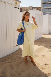 Robe ample à poches latérales portée par une femme, vue de trois-quarts, sac bleu, cabines