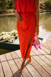 Robe fluide à col montant portée par une femme, vue rapprochée, fente, escarpins fuchsia