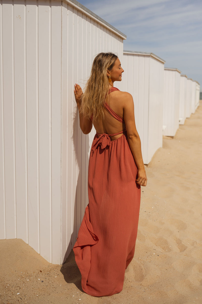 Robe fluide dos ouvert portée par une femme, vue de dos, cabines blanches, sable