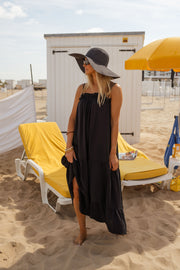 Robe à bretelles volantées portée par une femme, silhouette entière, transat jaune, chapeau noir