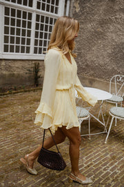 Robe courte à manches évasées portée par une femme, en marchant, table de jardin, sac noir