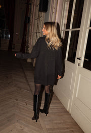 Robe pull brillante portée par une femme, silhouette entière, bottes, parquet