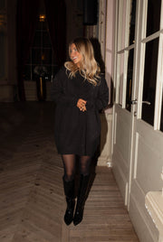 Robe pull brillante portée par une femme, silhouette entière, fenêtres, bottes