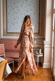 Robe longue fluide col V portée par une femme, silhouette entière, fente, canapé