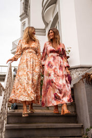 Robe longue fluide col V portée par deux femmes dans un escalier
