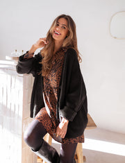 Robe léopard effet soie portée par une femme, vue de trois-quarts, gilet noir, collants