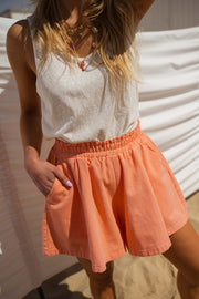 Short taille haute élastiqué orange porté par une femme, vue rapprochée, short froncé, débardeur