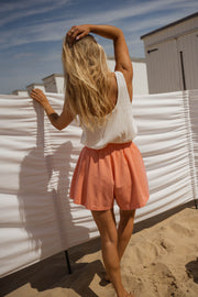 Short taille haute élastiqué orange porté par une femme, en marchant, plage, sable