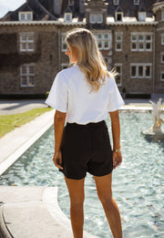 Short taille haute boutonné porté par une femme, vue de dos, bassin, t-shirt blanc
