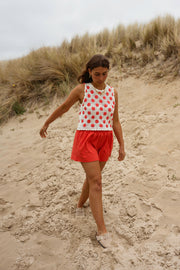 Short en coton effet délavé porté par une femme, en marchant, sable, haut à fleurs rouges