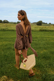 Short effet lin à nouer porté par une femme, vue de dos, prairie, sac en paille