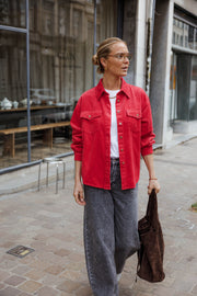 Surchemise en velours ample rouge portée par une femme, silhouette entière, sacs à la main