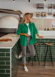Surchemise fluide en velours verte portée par une femme, silhouette entière, carrelage vert, tabourets