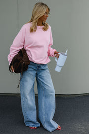 Sweat ample col rond porté par une femme, silhouette entière, sac marron, jean large, gobelet à la main
