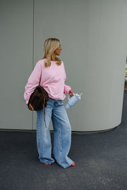 Sweat ample col rond porté par une femme, silhouette entière, jean large, gobelet, de loin