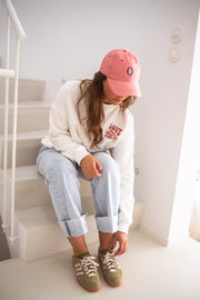 Sweat à col rond blanc porté par une femme, assise, escalier blanc, baskets