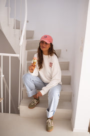 Sweat à col rond blanc porté par une femme, assise, escalier blanc, glace