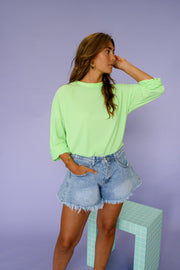 T-shirt rayé ample manches longues porté par une femme, silhouette entière, short en jean, main dans les cheveux
