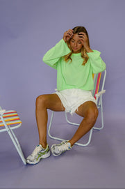 T-shirt rayé ample manches longues porté par une femme, assise, sur une chaise de plage