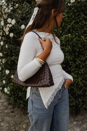 T-shirt moulant à dentelle asymétrique porté par une femme, vue de profil, sac marron à l'épaule