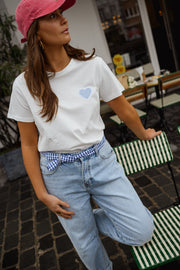 T-shirt blanc à cœur vichy bleu porté par une femme, silhouette entière, casquette rose, jean clair