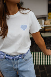 T-shirt blanc à cœur vichy bleu porté par une femme, vue rapprochée, cœur bleu, jean clair, ceinture vichy