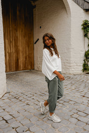 T-shirt resserré à la taille porté par une femme, vue de profil, pantalon vert-gris