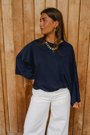 T-shirt à manches chauve-souris porté par une femme, vue rapprochée, collier doré, manches chauve-souris