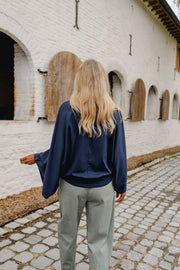 T-shirt à manches chauve-souris porté par une femme, vue de dos, sur des pavés