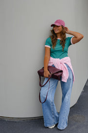T-shirt moulant manches courtes porté par une femme, silhouette entière, main sur la casquette